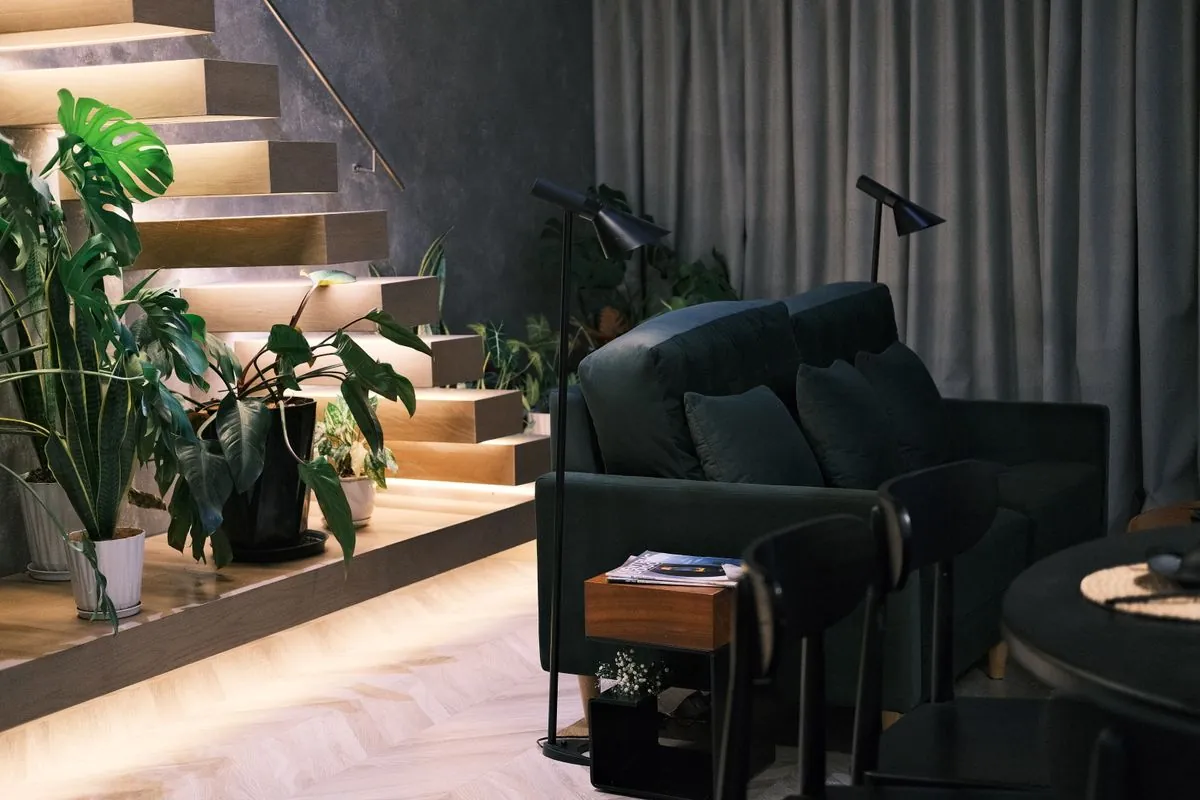 A dark stair hall with plants and a green sofa