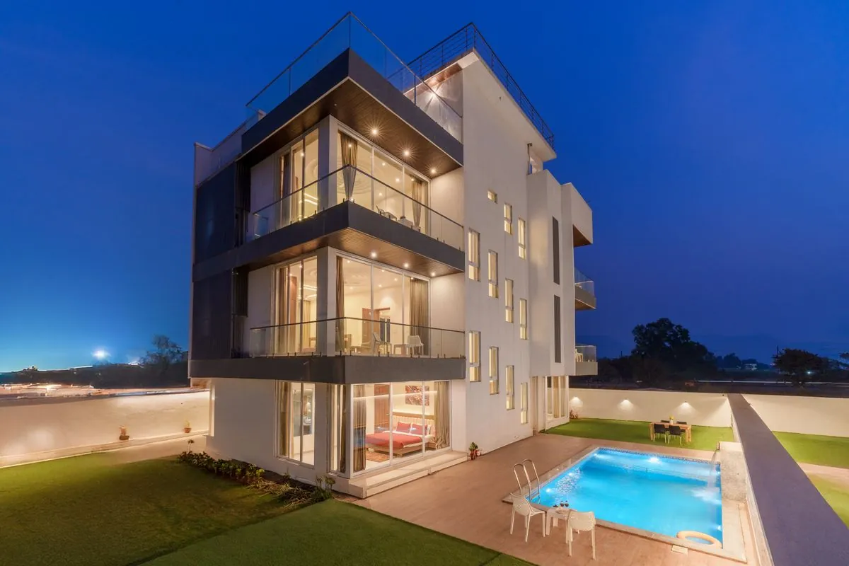 A white modern villa with a pool at dusk