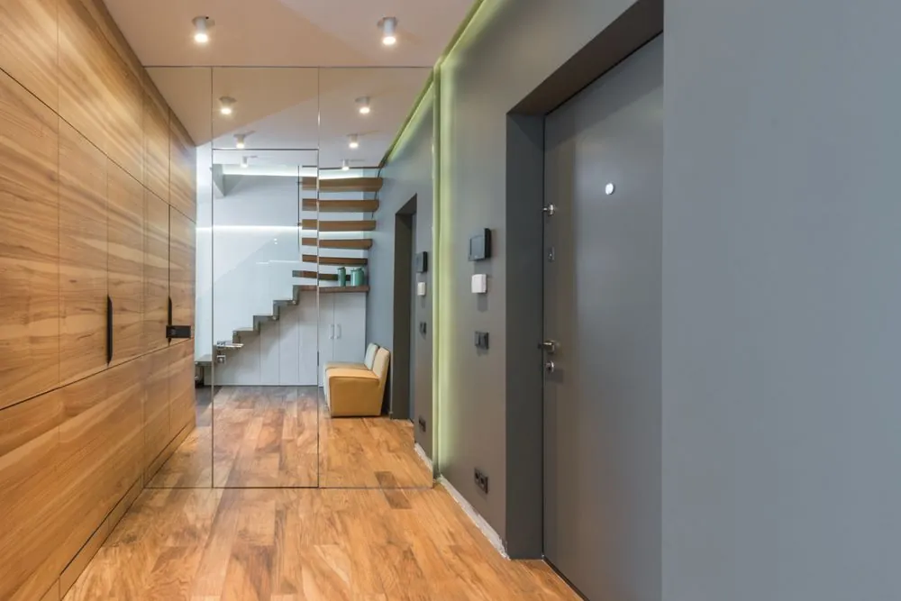 A hallway with a wooden staircase and a glass wall